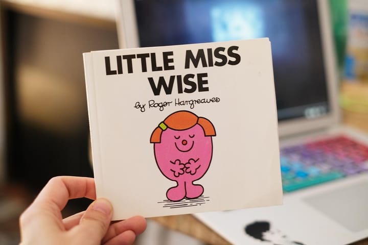 A hand holding the book Little Miss Wise by Roger Hargreaves