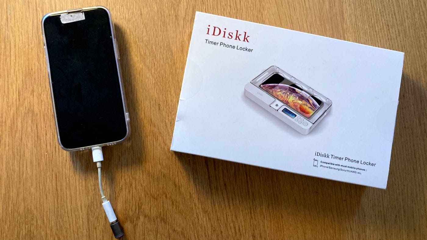 A photo of my smartphone next to a box from iDiskk showing its Timer Phone Locker